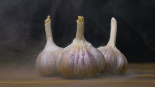 garlic bulbs are on the table in cold, steam from frost in slow motion, cloese up