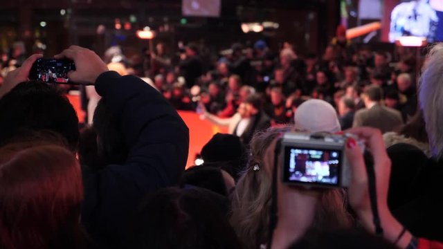 Crowd and fans taking photographs on mobile phones at a red carpet film festival event