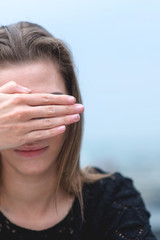 Young woman covers his face by hand 