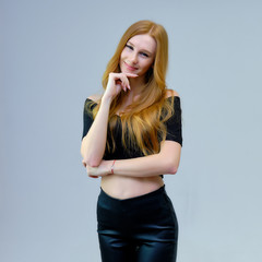 Concept portrait of a cute beautiful red-haired girl talking on a gray background in the studio