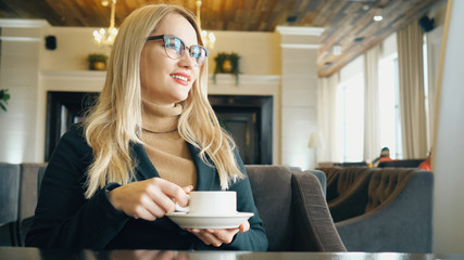 Happy girl drinking coffee and relaxing in cafe.