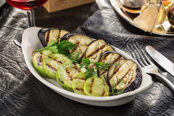 Grilled eggplant and zucchini slices on white plate served on the table