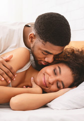 Obraz na płótnie Canvas Handsome man kissing woman on cheek under in bed
