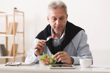 Senior businessman having lunch break, eating salad