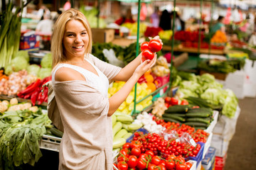 Cute young woman buying vegetables at the market
