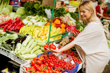 Cute young woman buying vegetables at the market