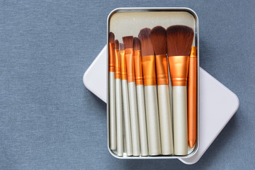 Set of professional cosmetic brushes in box on grey background. Top view point, flat lay. Copy space