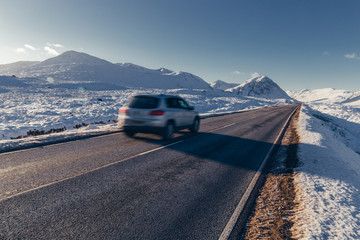 Car driving on open road winter snow mountain landscape in Glencoe Scotland