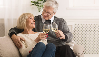 Happy mature couple drinking white wine at home