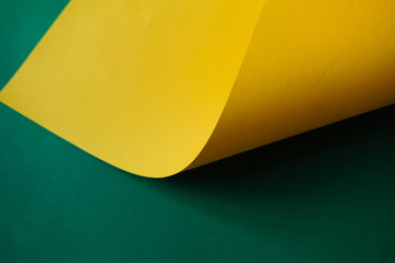 The bright yellow sheet paper on a green background. Monochrome color paper design.