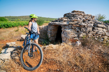 Woman traveler ride bicycle in the historic site on Stari Grad plain, UNESCO world heritage site in Hvar island, Dalmatia, Croatia - obrazy, fototapety, plakaty