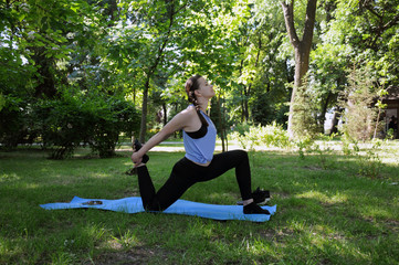 Sports girl doing yoga in the city park. Healthy lifestyle