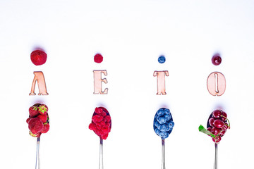 Top view of berries mixed (strawberries, raspberries, blueberries and blackberries) on metal spoons on white background. Food concept. Flat lay. Nature concept. A place for your inscription.