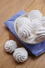 Fototapeta na wymiar Small white meringues in a bowl on wooden table
