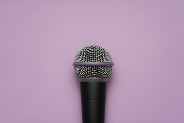 Close-up of a vocal microphone in the center of purple background. 