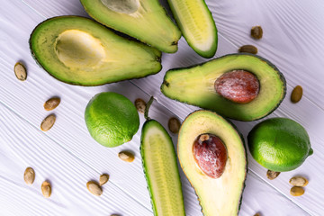 Avocado, cucumber, lime, pumpkin seeds on a white wooden table, healthy food.