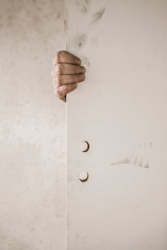 une main derri&egrave;re une porte