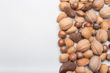 Different kinds of nuts in the shell, hazelnut, walnut, almond and brazil nuts on gray concrete background, horizontal, copy space, top view