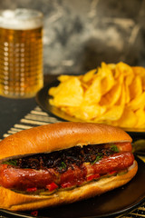 Hotdogs with glass of beer with french fries on wooden board