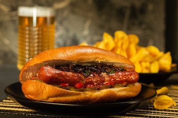 Hotdogs with glass of beer with french fries on wooden board