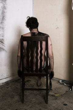 Homme assis sur une chaise, le dos sale