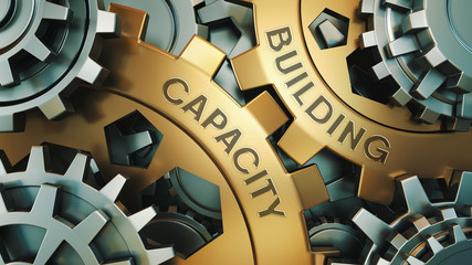 Capacity Building - Concept. The inscription on the golden cogwheels. In the background is a clock or engine mechanism. 3d illustration