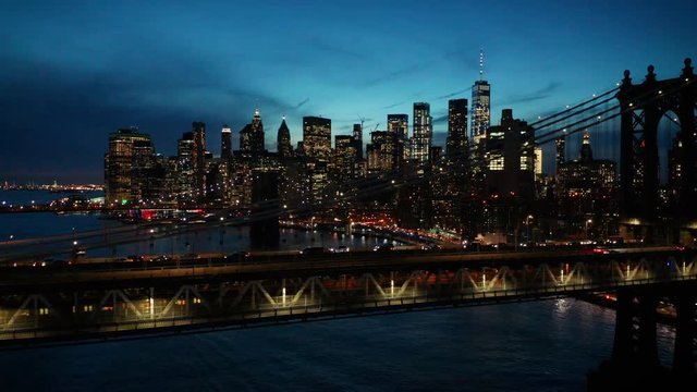 night flying alongside Manhattan Bridge with downtown in BG
