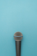 Vocal microphone on light-blue background. Vertical