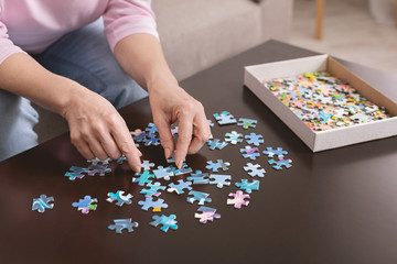 Elderly woman hands doing jigsaw puzzle closeup