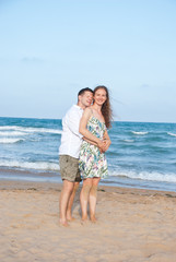 Fototapeta na wymiar Image of couple hugging by the sea in Spain on their honeymoon. Happy family vacation.