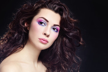 Fototapeta premium Portrait of young beautiful woman with long curly hair and fancy make-up