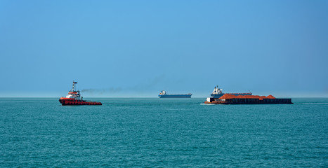 Tug boat with a large cargo barge transporting bauxite ore in Kamsar, Guinea.