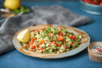 Tabbouleh salad with quinoa. Eastern food with vegetables mix, vegan diet. Side view, old plate