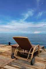 Lounger on the edge of the wooden pier overlooking the sea.