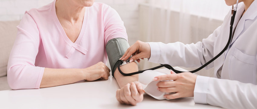 Doctor checking blood pressure of senior patient
