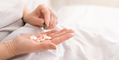 Obraz na płótnie Canvas Senior woman holding pills in hand close-up