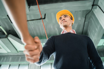 low angle shoot of businessman with hardhat shaking hand