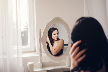 Fashion portrait of young sensual woman looking in mirror 