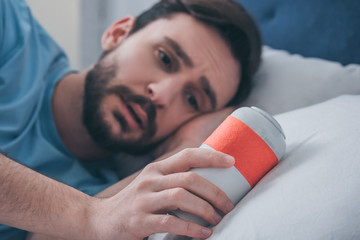 grieving man lying in bed and holding funeral urn