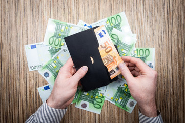 investing money euro in an envelope with male hands on background of banknotes.