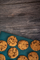 Vertical image of chocolate chip cookies on a blue cloth, with copy space