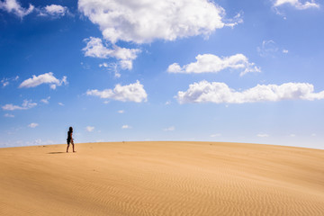 woman walking on dunes in maspalomas, spain
