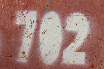 number seven hundred two painted on rusty red metal, number 702