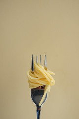 Pasta on a fork. Beige background