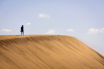 woman walking on dunes in maspalomas, spain