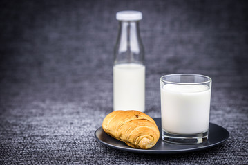 Croissant on a plate with a glass of milk