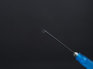 A drop of medicine on the end of a medical syringe needle.