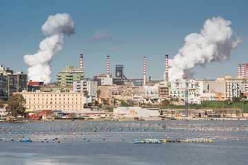 White smoke going up from the chimney of steel plant of  Taranto, Puglia. Italy