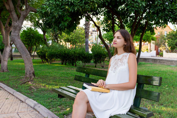 Naklejka premium Young woman is holding a book and dreaming about something outside