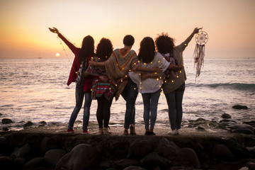 Fototapeta premium Dreaming image with group of females friends hug each other all together looking the sunset for friendship and love concept - Forever friends and dream lifestyle concept - people enjoying and feeling 